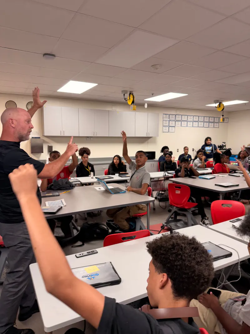 Students raising their hands during an interactive classroom learning experience.