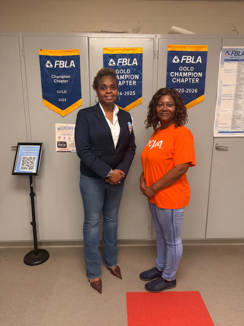 Pamela Coleman with a community supporter in front of FBLA Gold Champion Chapter banners.