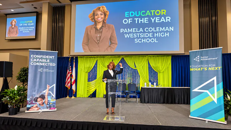 Pamela Coleman on stage beneath her 2026 Junior Achievement Educator of the Year recognition.